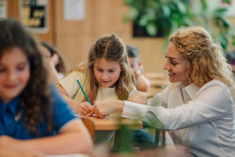 Teacher helping young girl with her studies in classroom
